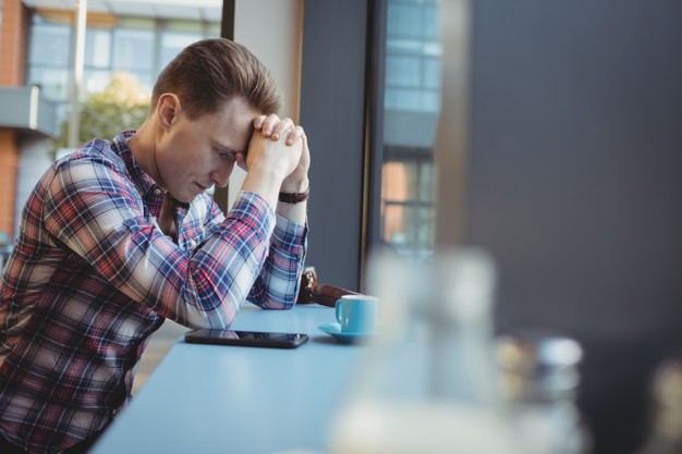 Upset man standing with hand on forehead 
