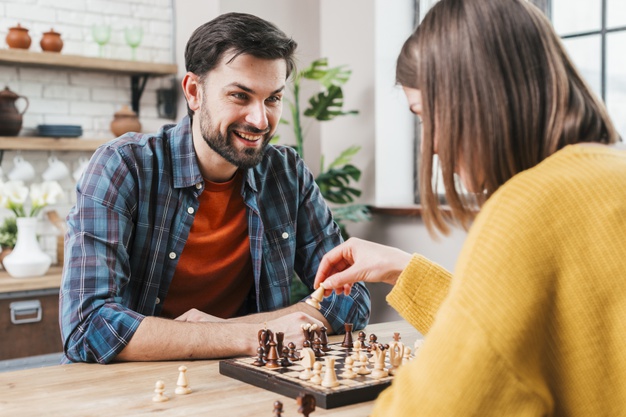 man playing chess with his wife at home