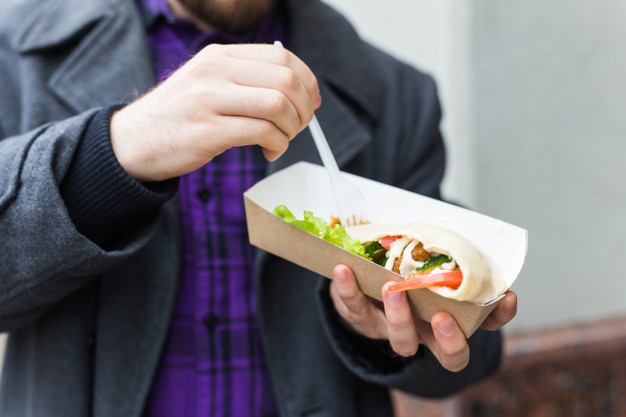 man is holding falafel sandwich in paper bag. healthy street food concept,
