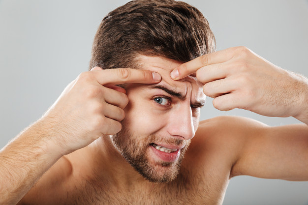 portrait of a man squeezing pimple