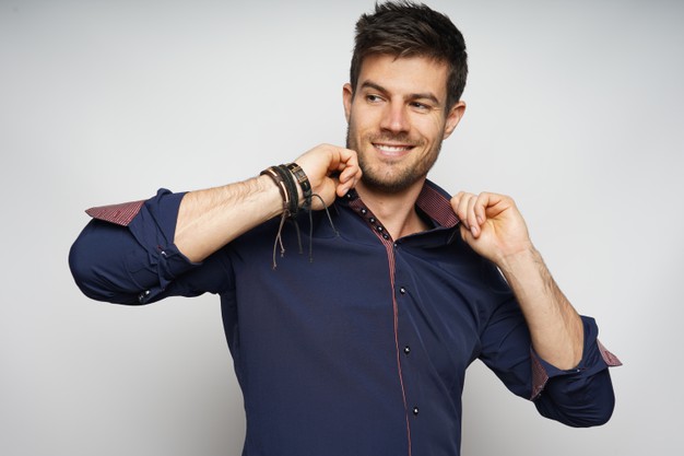 smiling male confidently holding his collar and isolated over white wall