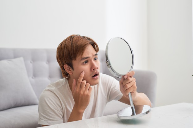 handsome-man-looking-himself-mirror-squeezing-pimple