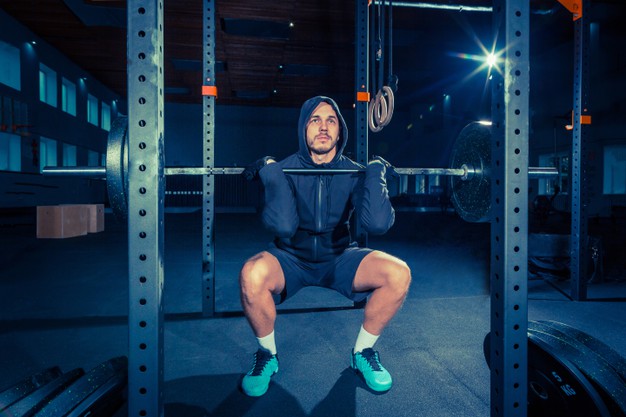 super fit muscular young man working out in gym with barbell