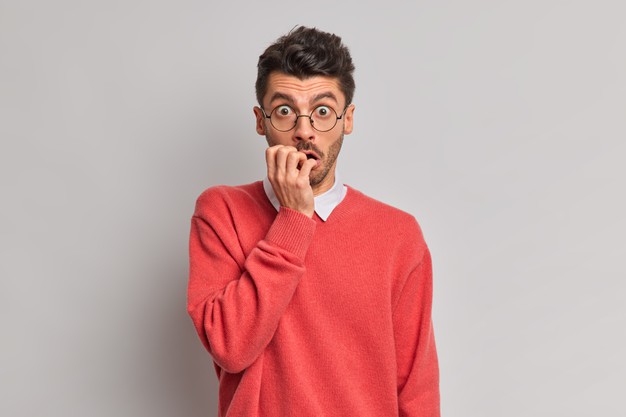 shocked-nervous-man-bites-finger-nails-stares-through-optical-glasses