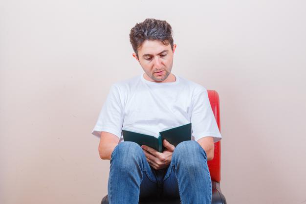  man reading book while sitting on chair