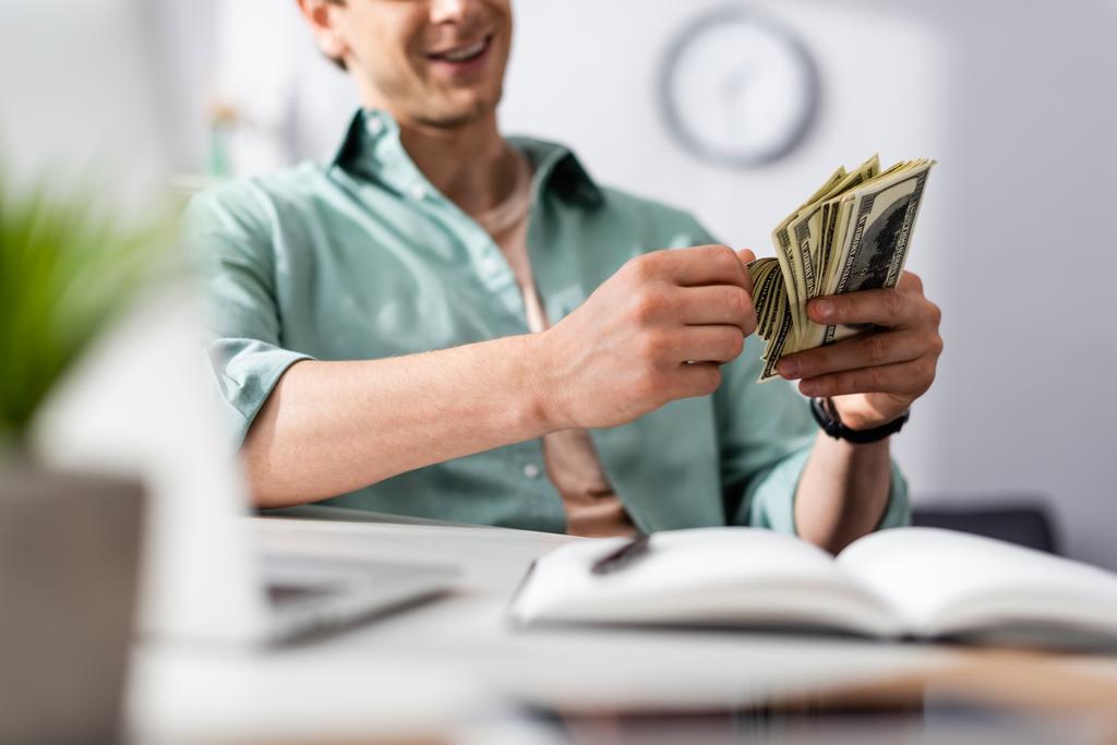 man holding money while sitting on chair
