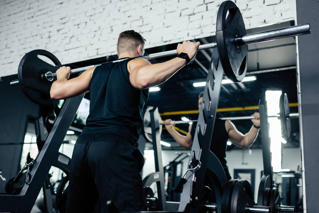 Sportsman lifting barbell during cross training in gym 