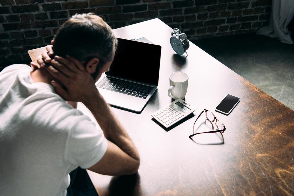 Depressed man touching head while sitting at workplace