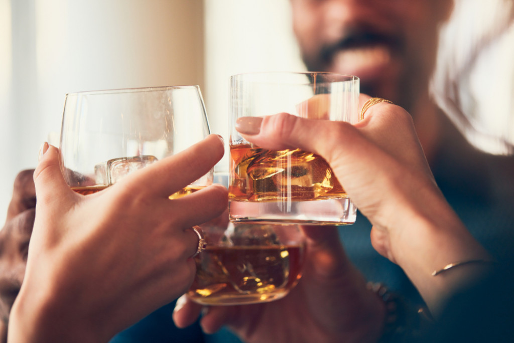 many people clinking glasses with alcohol at a toast