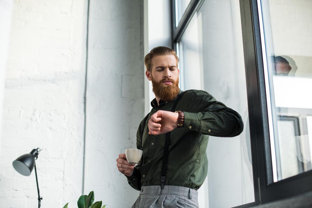 businessman holding cup of coffee and checking time