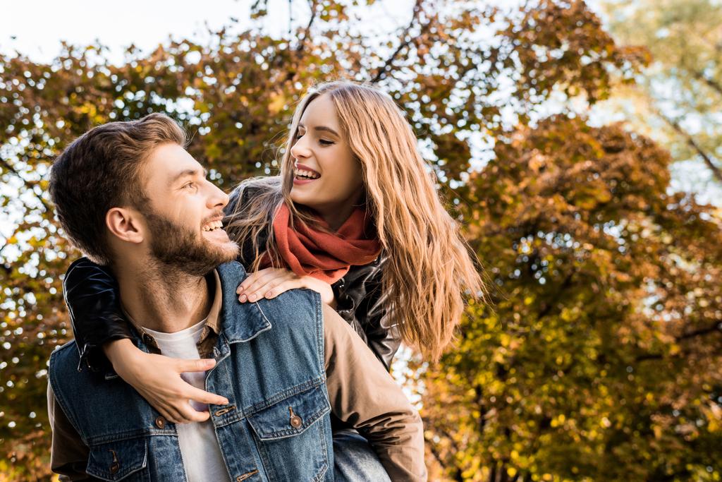happy couple in love piggybacking in autumn park