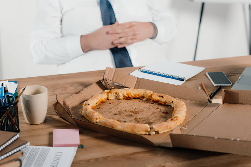  fat businessman eating pizza at workplace