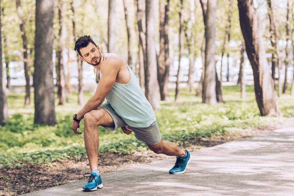Handsome young sportsman looking away while working out in park