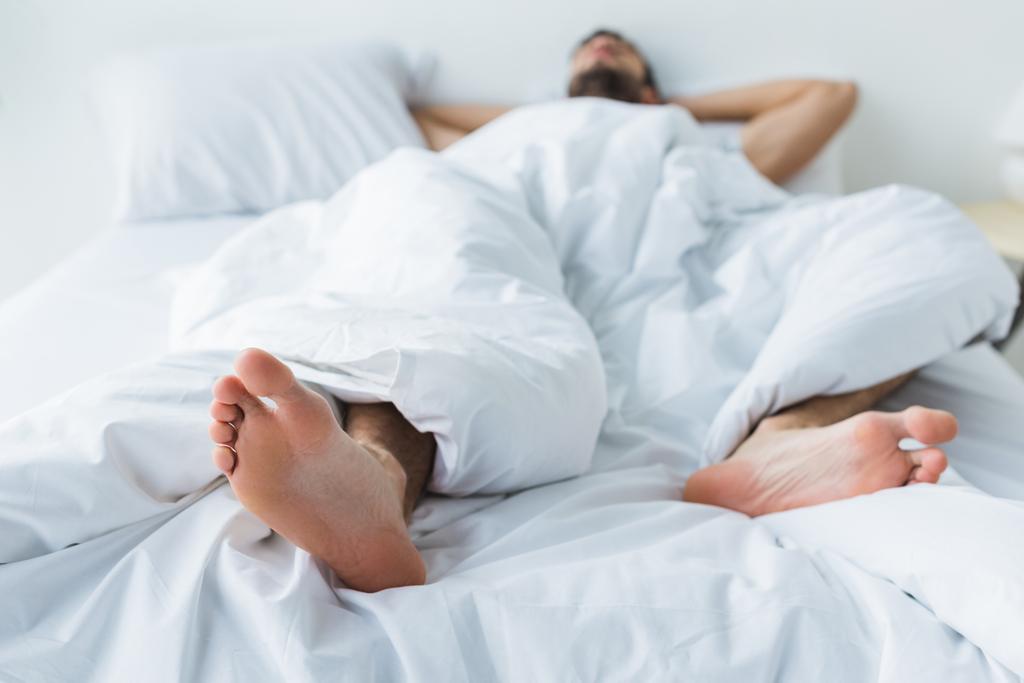 man sleeping on bed, feet on foreground