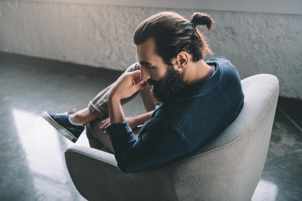 Thoughtful young businessman sitting in armchair