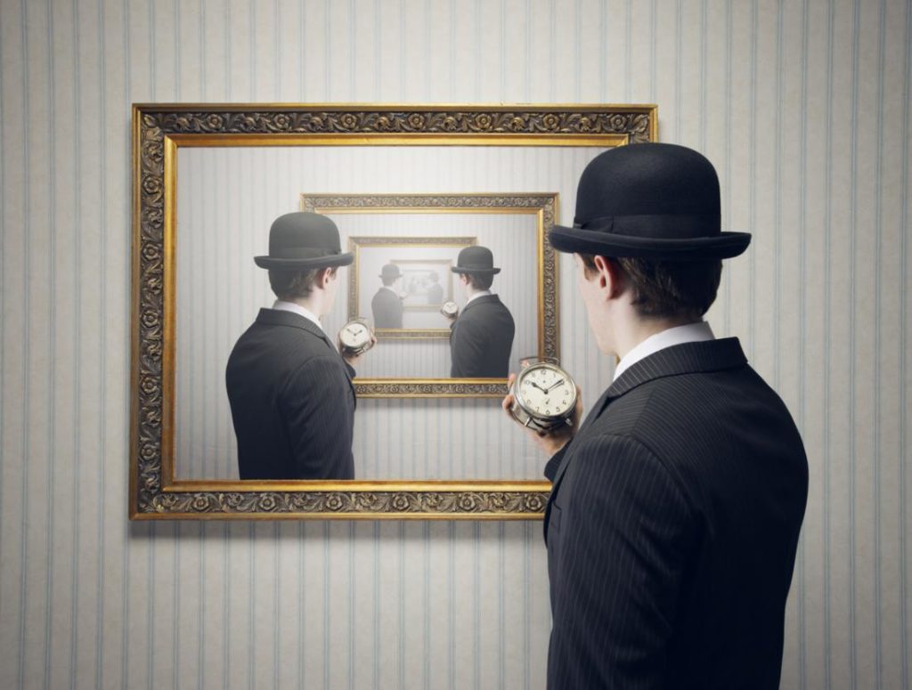 man with hat holding a clock