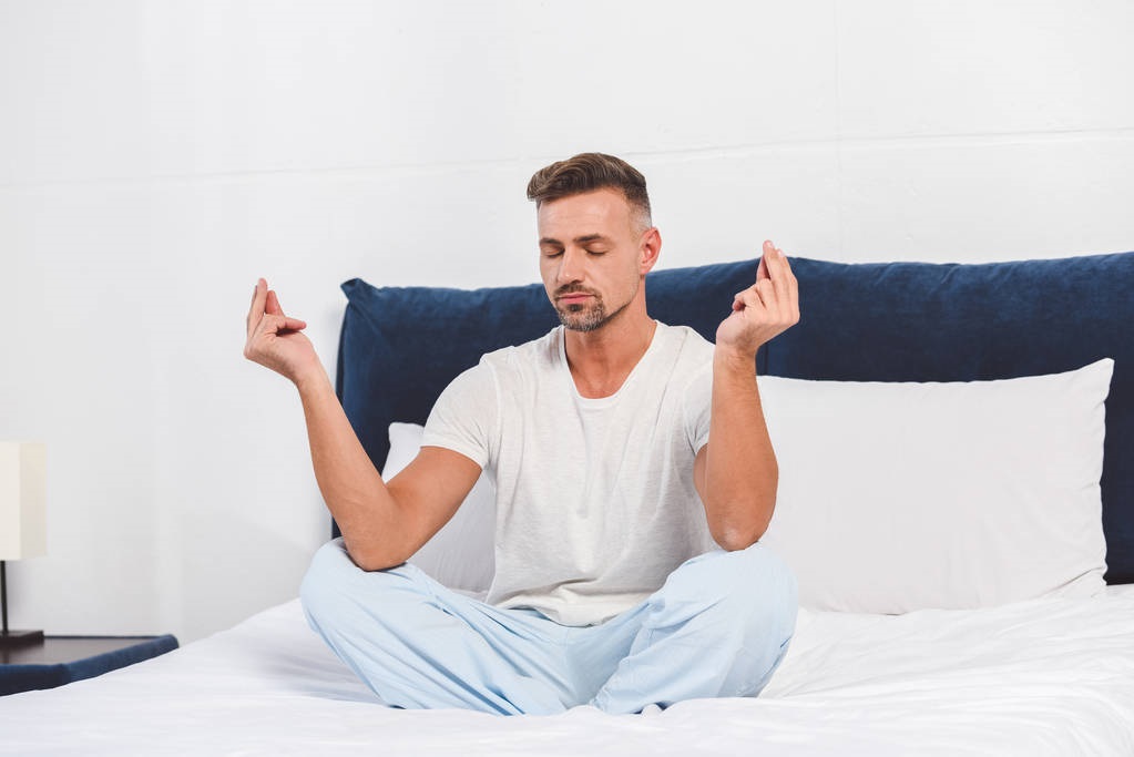 man practising yoga in bedroom