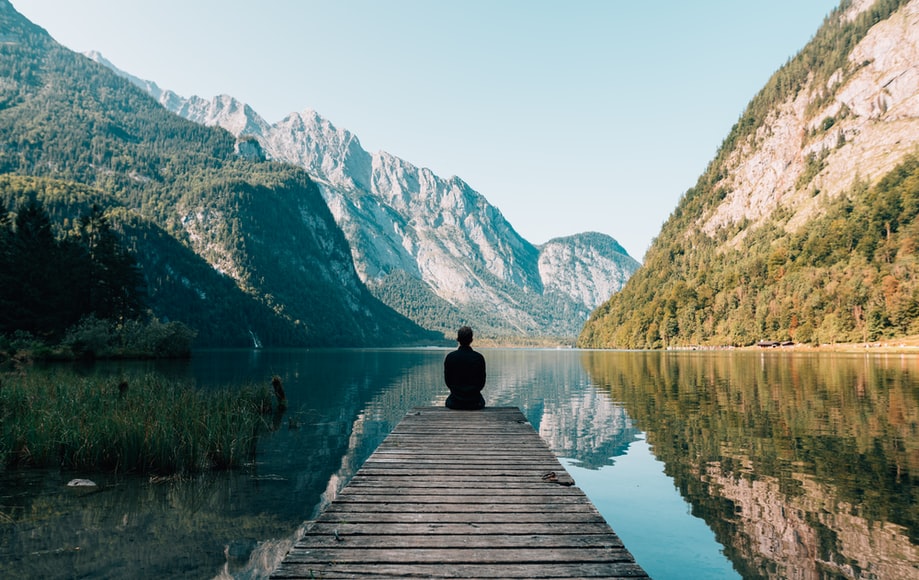 man sitting on the bridge of lake
