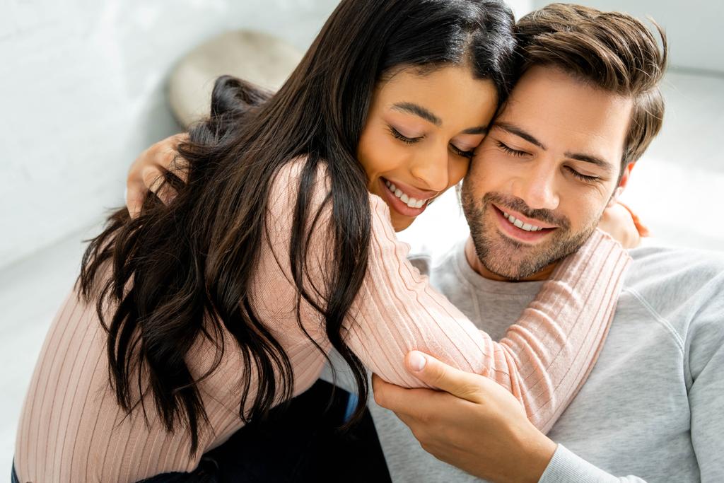 woman and handsome man smiling and hugging in apartment
