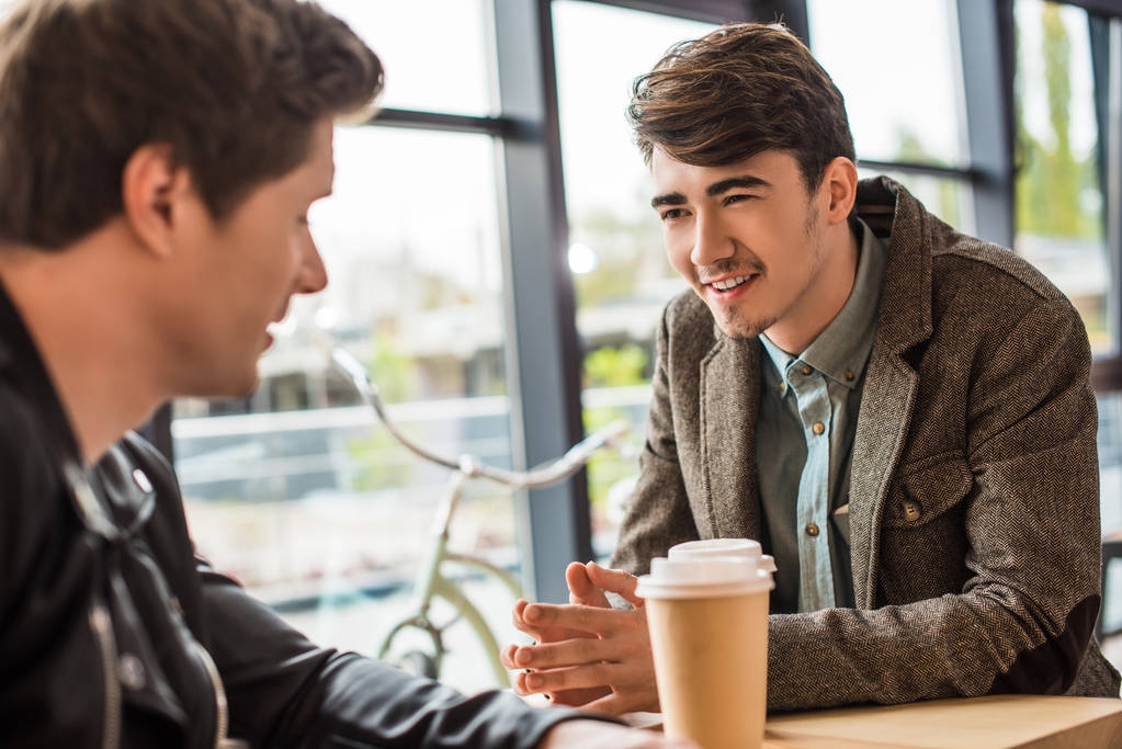 men talking and sitting with a coffee in a cafe