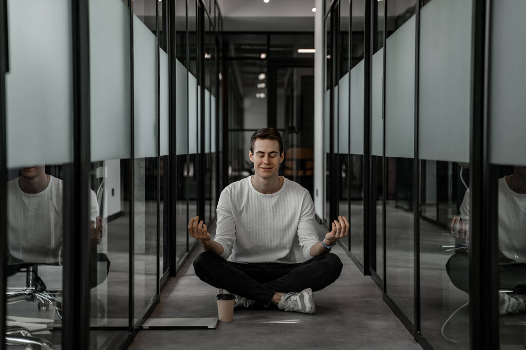 Student with closed eyes meditating in hall 