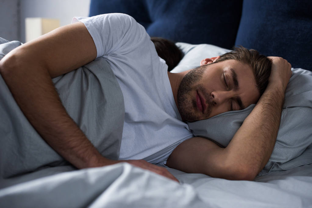 man sleeping by his wife in bed