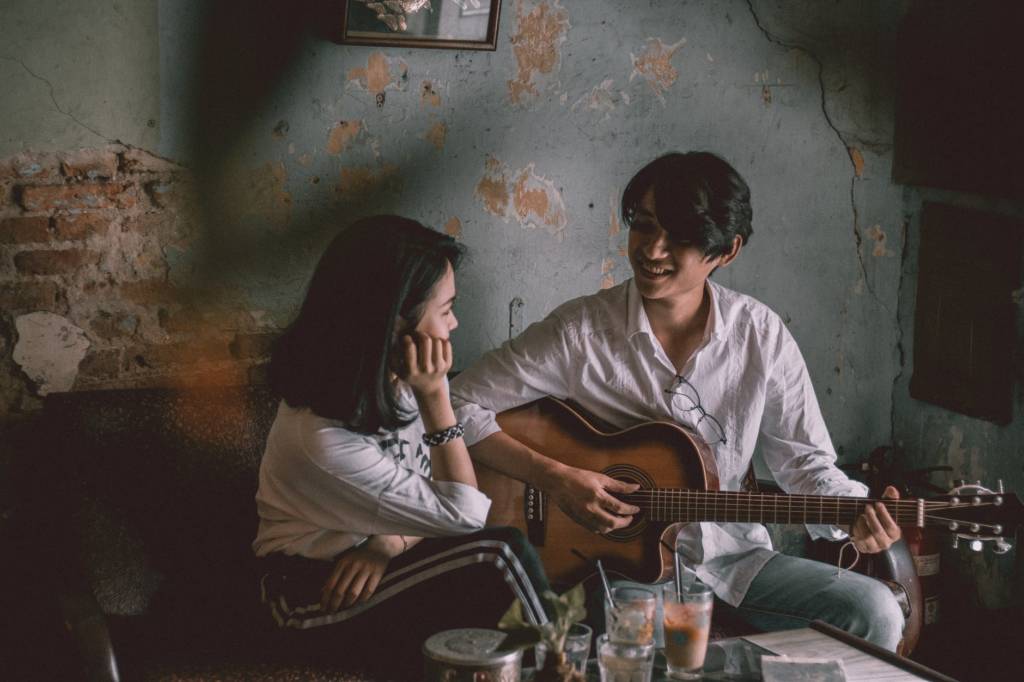 Man Playing Guitar In Front of A Girl
