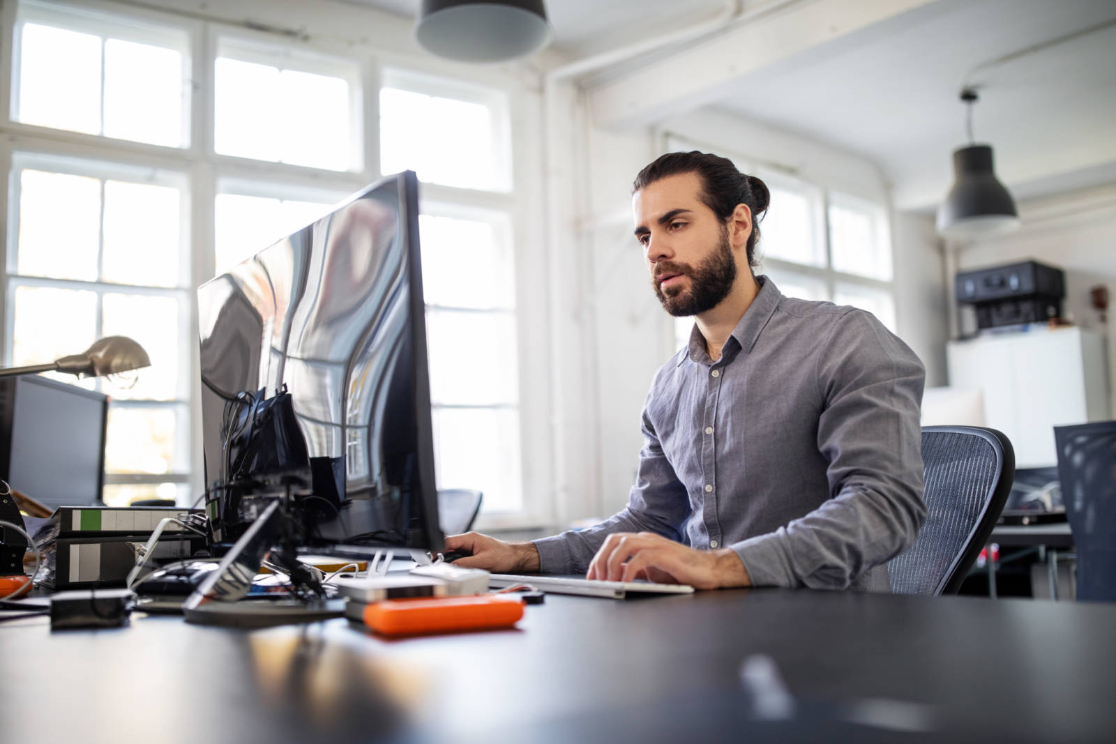 Young businessman sitting at his work desk and working on desktop computer