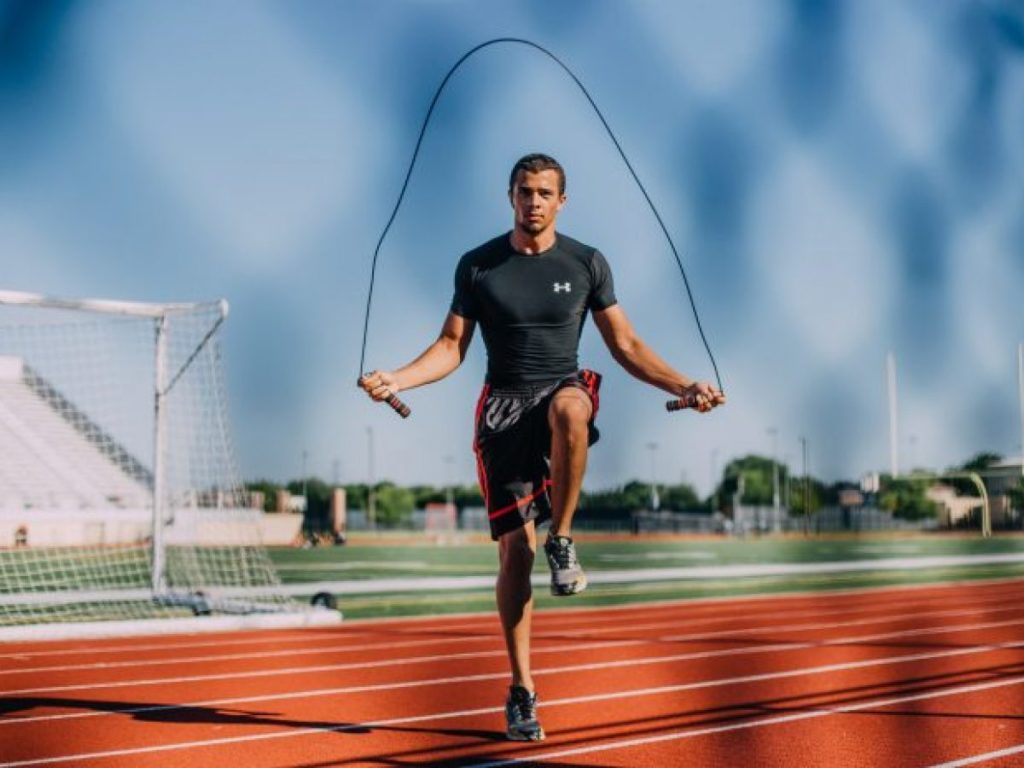 A young man jumps rope on the track of a football field
