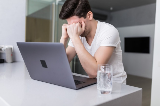 Frustrated with problems young business man working on laptop at home