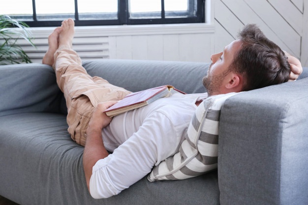 Handsome man sleeping on the couch with a book