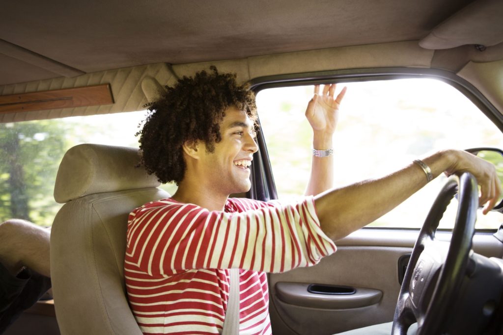 Happy Young Man Driving Car And Smiling