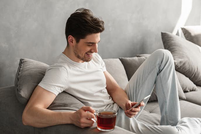 Handsome man in basic t-shirt smiling and holding mobile phone 