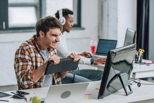 angry programmer holding keyboard