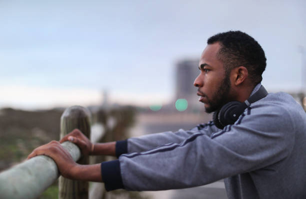 An African man resting against a fence post