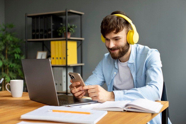 Young man listening to music on headphones while working 