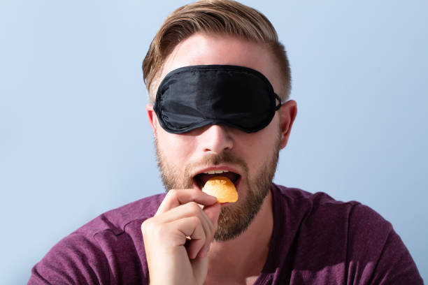 Portrait Of Blindfolded Young Man Tasting Food