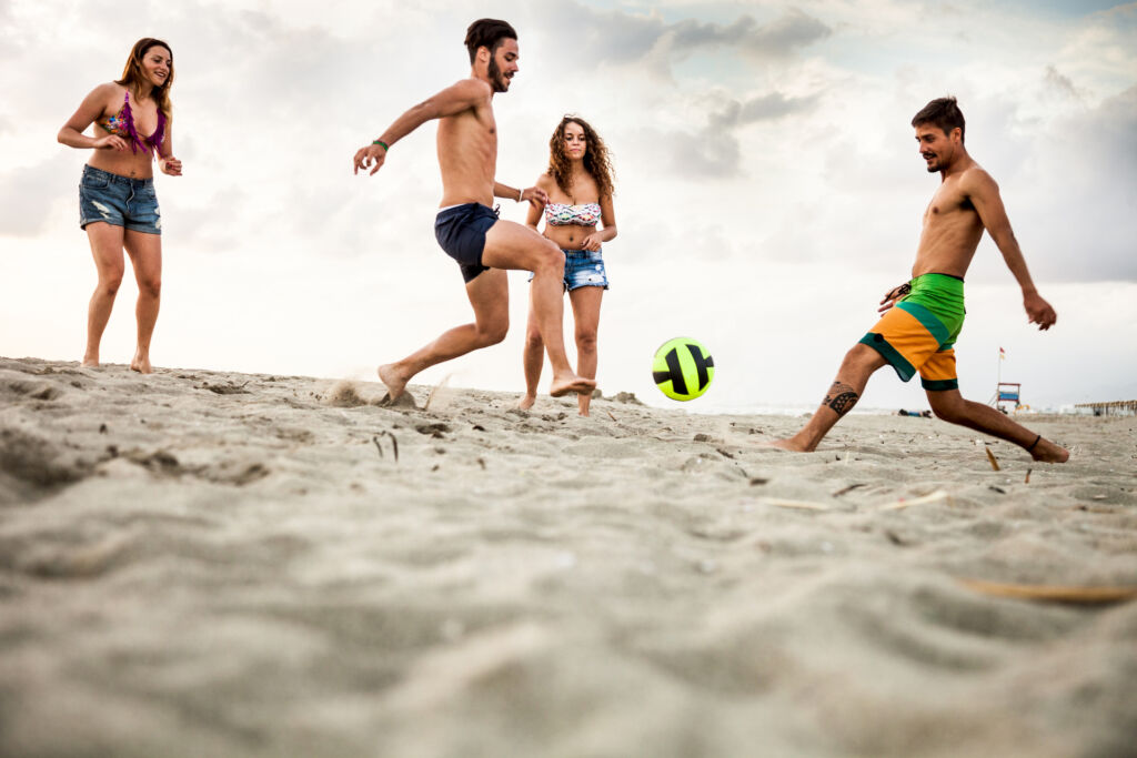 Friends playing soccer on the beach