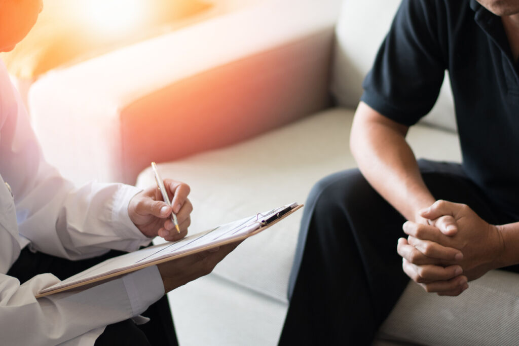 Doctor physician consulting with male patients in hospital psychology clinic exam room. 
